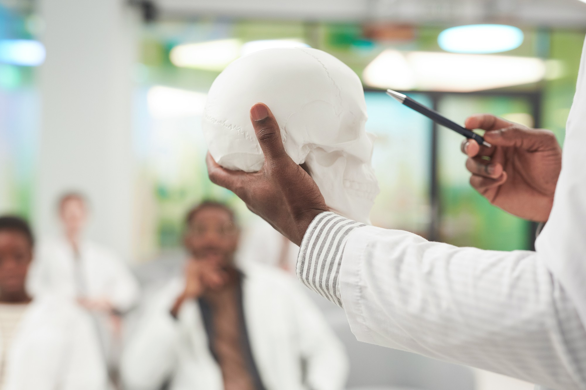 close-up-unrecognizable-african-american-man-holding-skull-model-while-giving-lecture-medicine-college-coworking-center